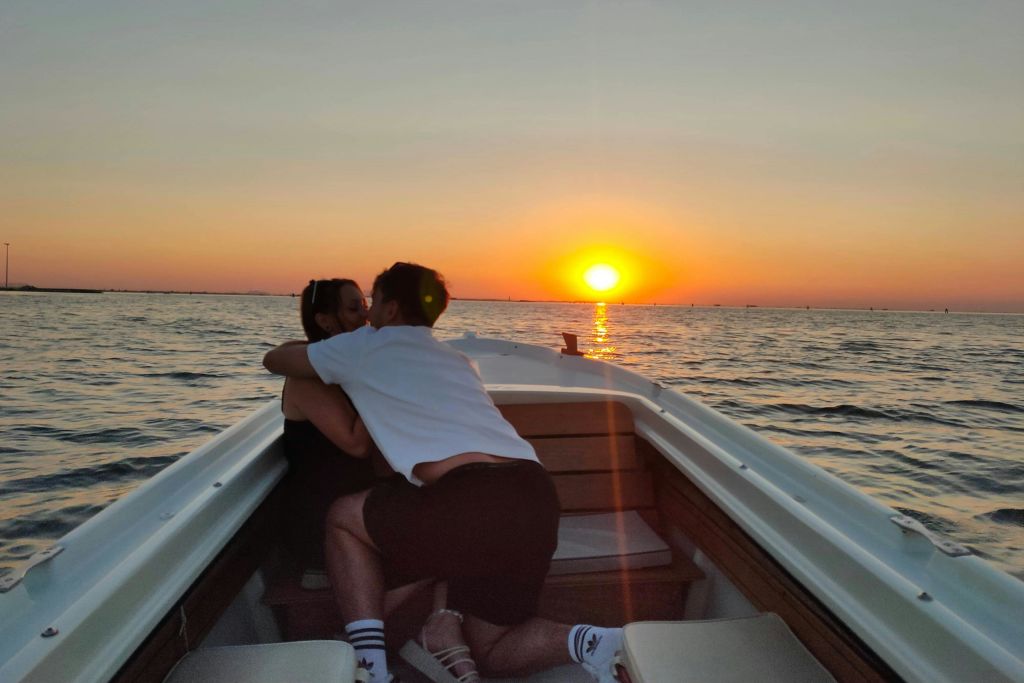 잔잔한 바다 위로 지는 석양에 작은 보트에 몸을 싣고 있는 두 사람.