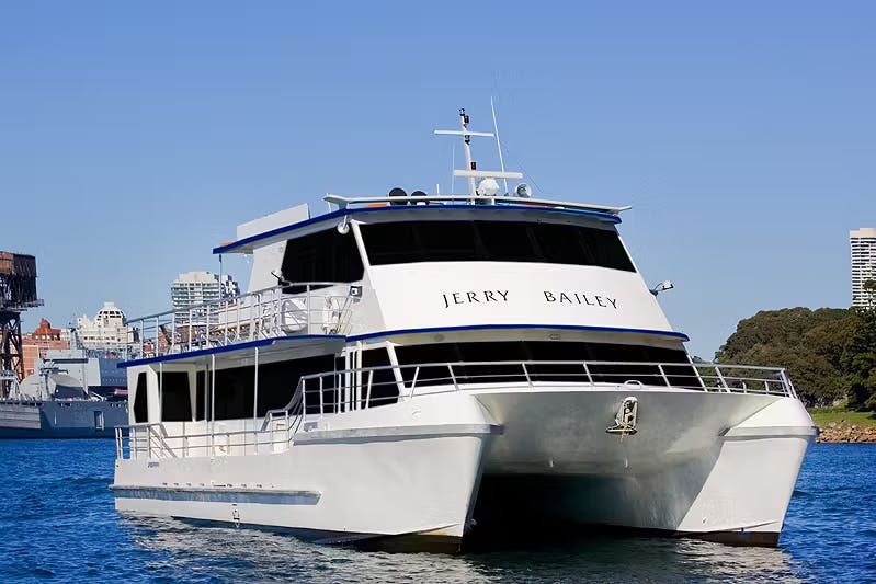 "제리 베일리" 라는 이름의 크고 하얀 여객선이 맑고 푸른 하늘 아래 물에 정박해 있습니다.