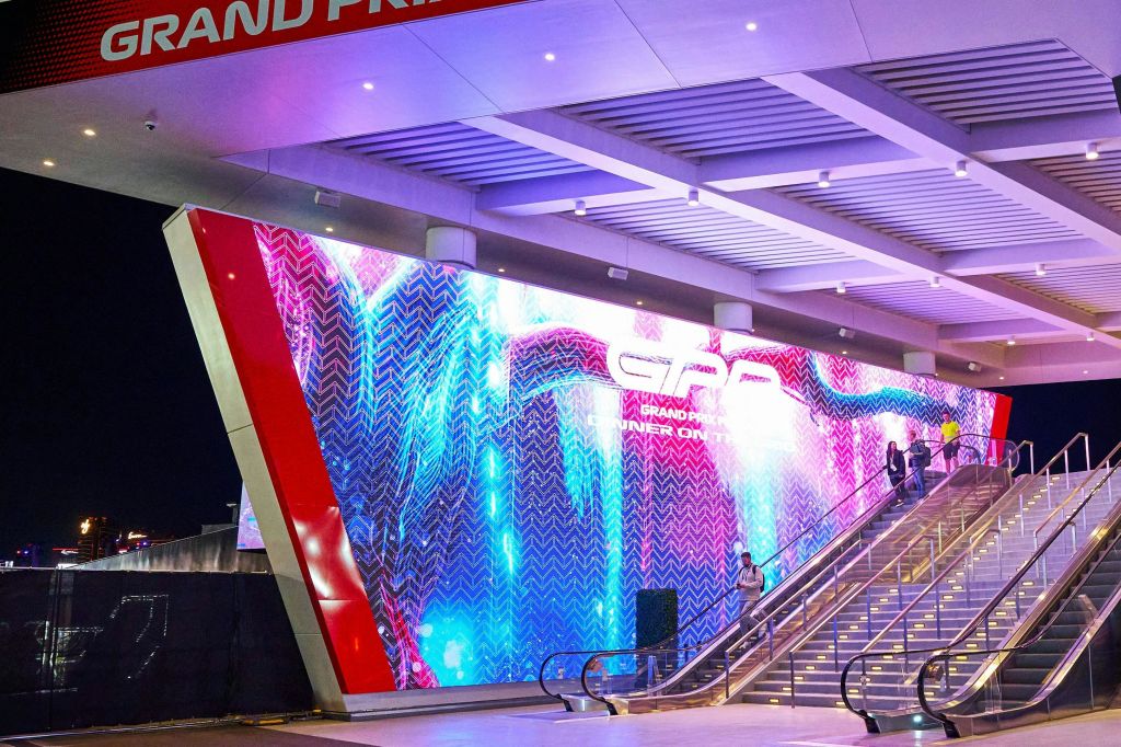 건물에 다채로운 그래픽이 있는 대형 LED 스크린. 사람들이 오르는 계단. 수평 빔이 있는 천장.