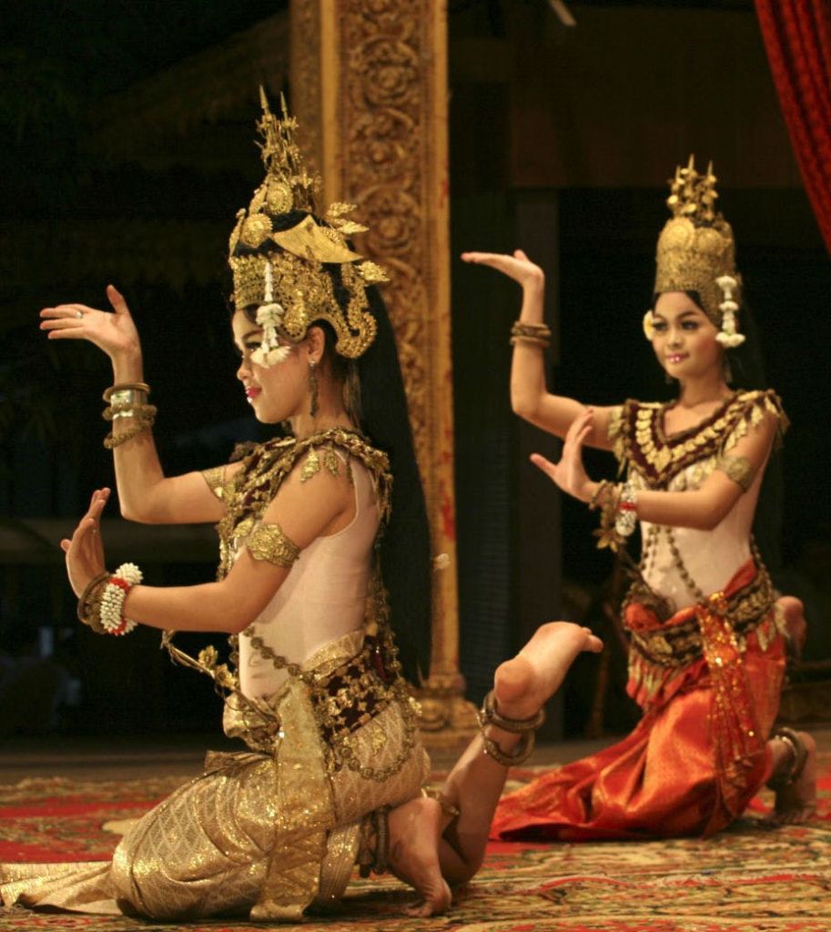 전통 복장을 한 두 무용수가 화려한 머리 장식과 정교한 의상을 입고 희미한 조명으로 클래식 댄스를 선보입니다.