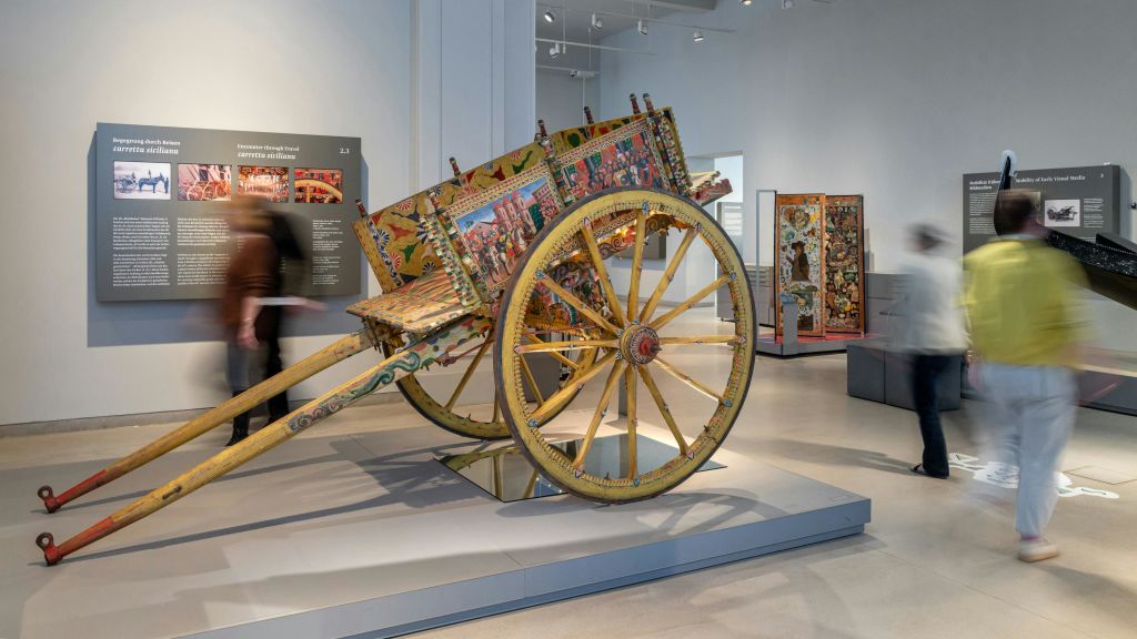 현대 미술관 전시관에는 커다란 바퀴가 달린 화려하고 화려한 나무 카트가 전시되어 있습니다.