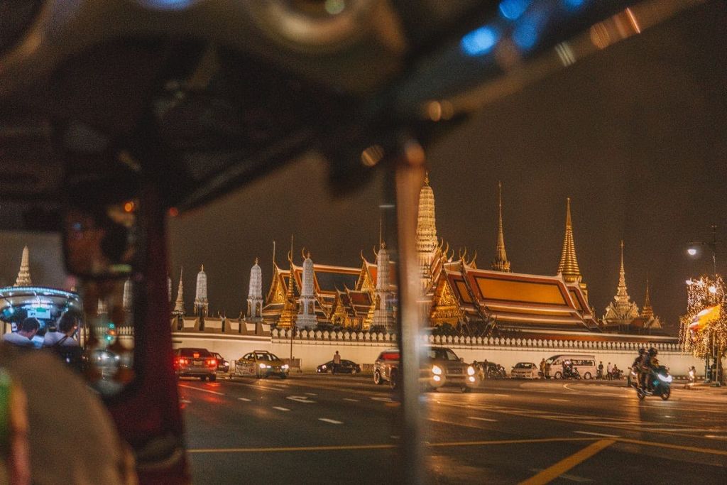 야간에는 첨탑이 있는 밝고 화려한 사원 단지를 감상할 수 있습니다. 자동차가 인접한 도로를 지나갑니다.