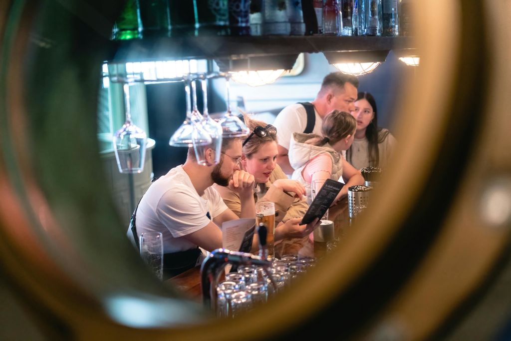 원형 프레임에 걸린 유리 제품과 선반이 보이는 바에 앉아 독서 메뉴를 즐겨보세요.