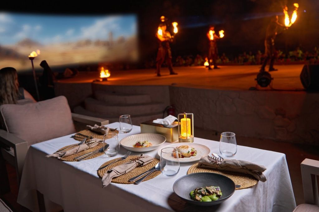공연자들이 관객들 앞에서 불을 다루고 있는 무대를 마주하고 있는 음식 접시가 놓인 테이블입니다.