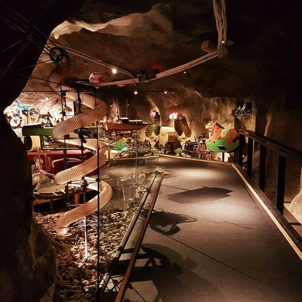 통로, 장난감, 파이프, 바위, 추상적인 설치물을 배경으로 어두운 조명을 자랑하는 지하 공간입니다.