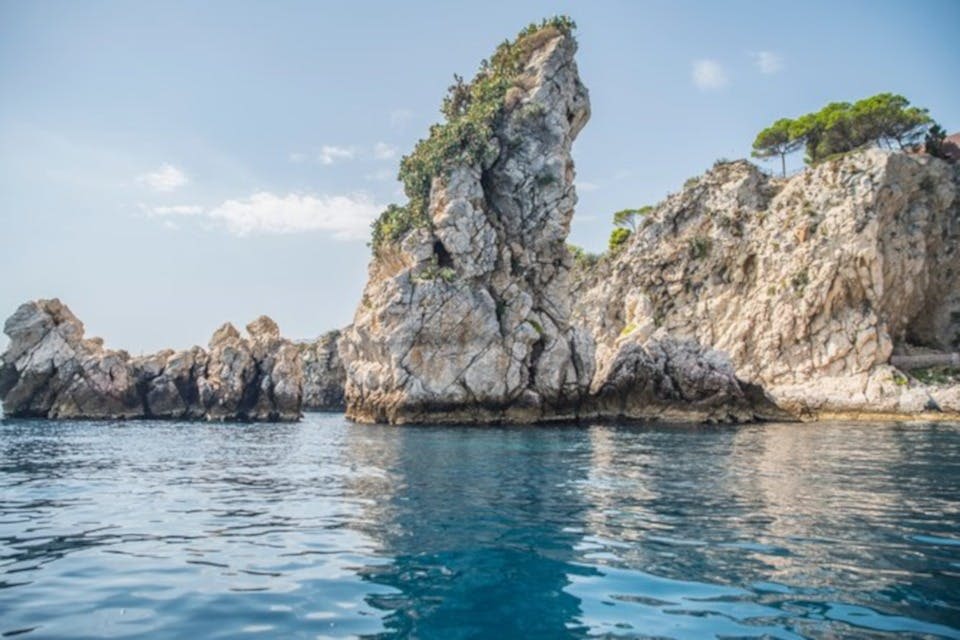 고요한 푸른 바다에서 바위 절벽이 솟아오르고, 커다랗고 들쭉날쭉한 바위 지층이 청명한 하늘 아래 희소한 초목으로 덮여 있습니다.
