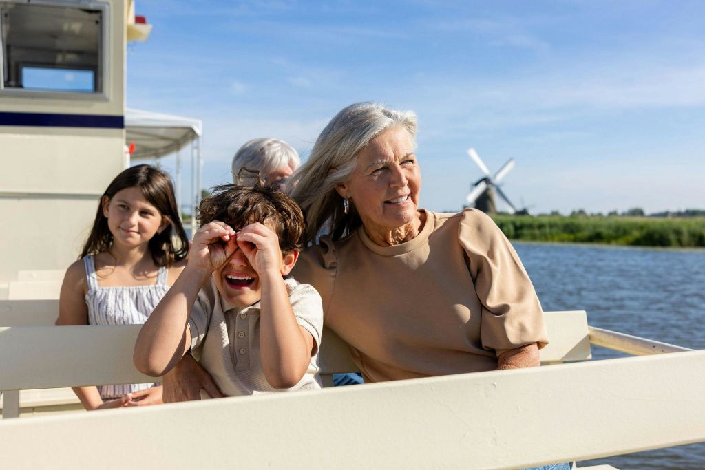 쌍안경을 사용하는 아이, 미소를 짓는 여성, 햇살이 내리쬐는 푸른 하늘 아래 야외 벤치에 앉아 있는 소녀.