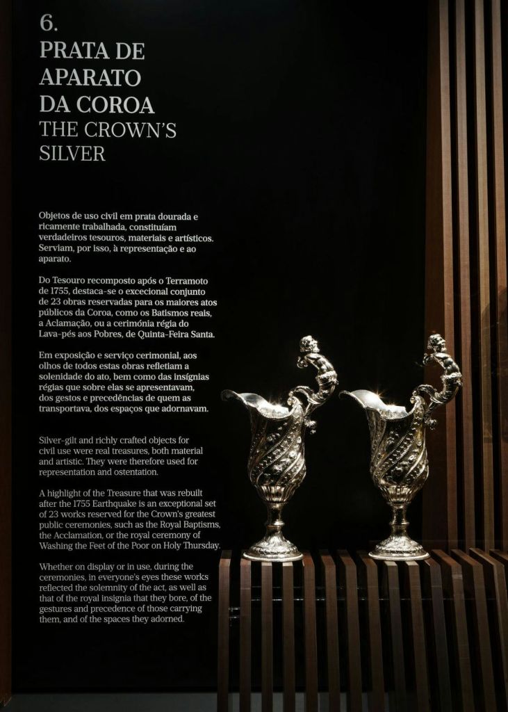 화려한 은색 투수 두 개가 나무 선반에 진열되어 있습니다. 왼쪽의 텍스트는 왕관의 은에 대한 정보를 제공합니다.