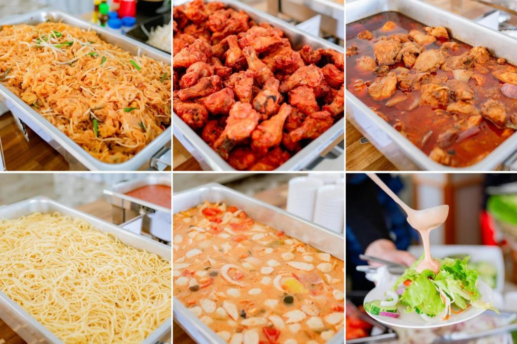 닭튀김, 파스타, 국수, 스튜, 샐러드 등 다양한 요리를 곁들인 뷔페. 배경에 양념이 보입니다.