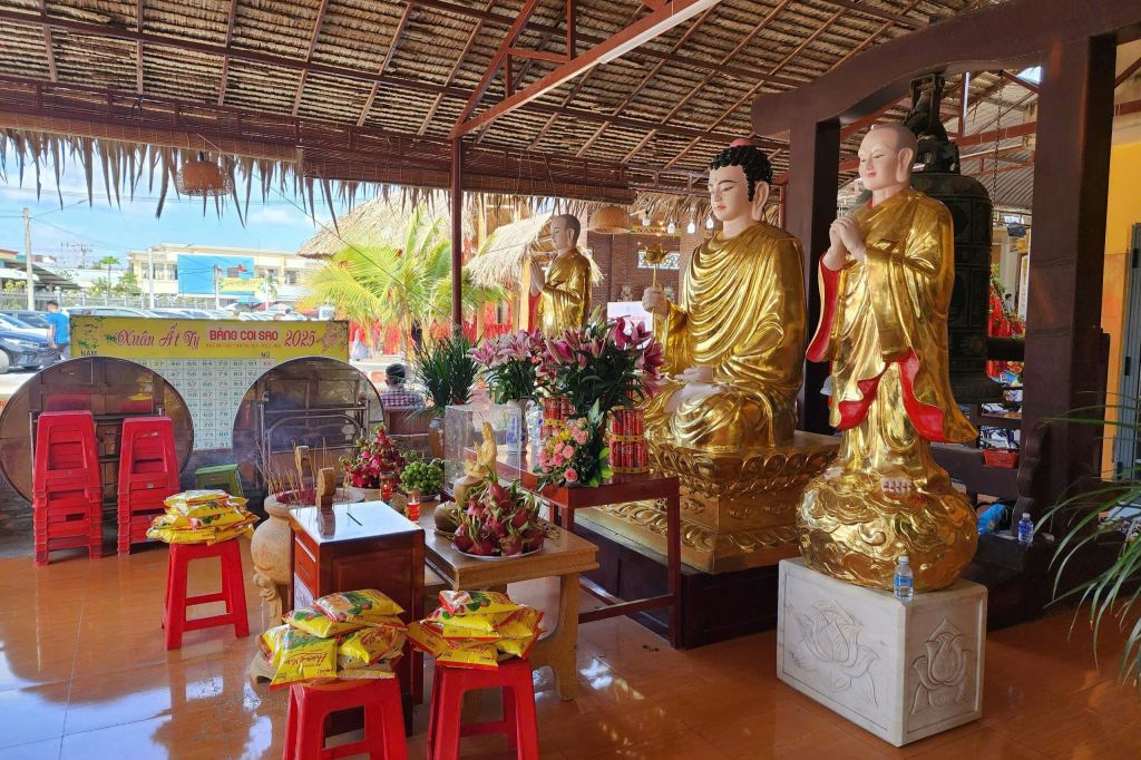 꽃과 제물, 커다란 종소리로 둘러싸인 사원의 황금 불상.