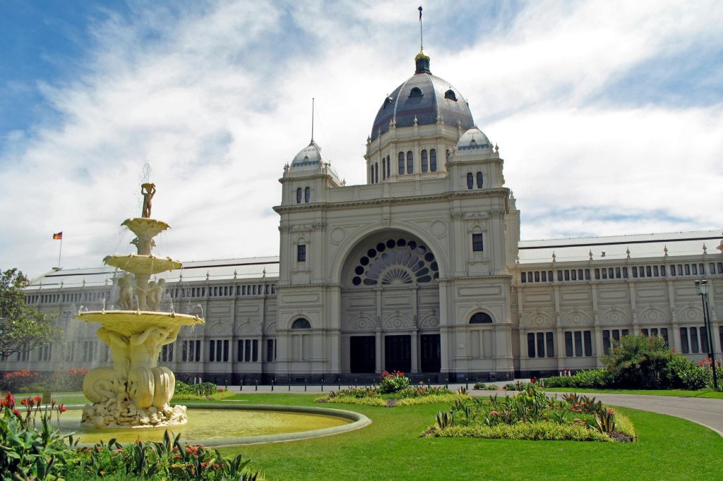 아치와 장식용 창문이 있는 화려한 돔형 건물로, 녹색 잔디밭과 전경의 분수로 둘러싸여 있습니다.