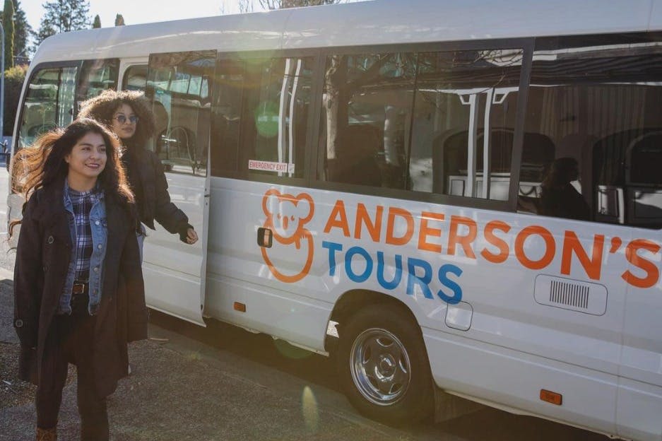 "Andes Tours" 가 적힌 흰색 밴을 빠져나오는 두 명의 여성이 햇살 가득한 거리에 주차되어 있습니다.