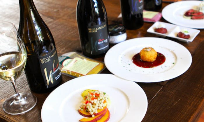 두 가지 요리, 하나는 쿠스쿠스와 복숭아 슬라이스, 다른 하나는 소스에 튀긴 음식과 함께 "윌리엄슨 와인" 이라는 라벨이 붙은 와인 병이 있습니다.