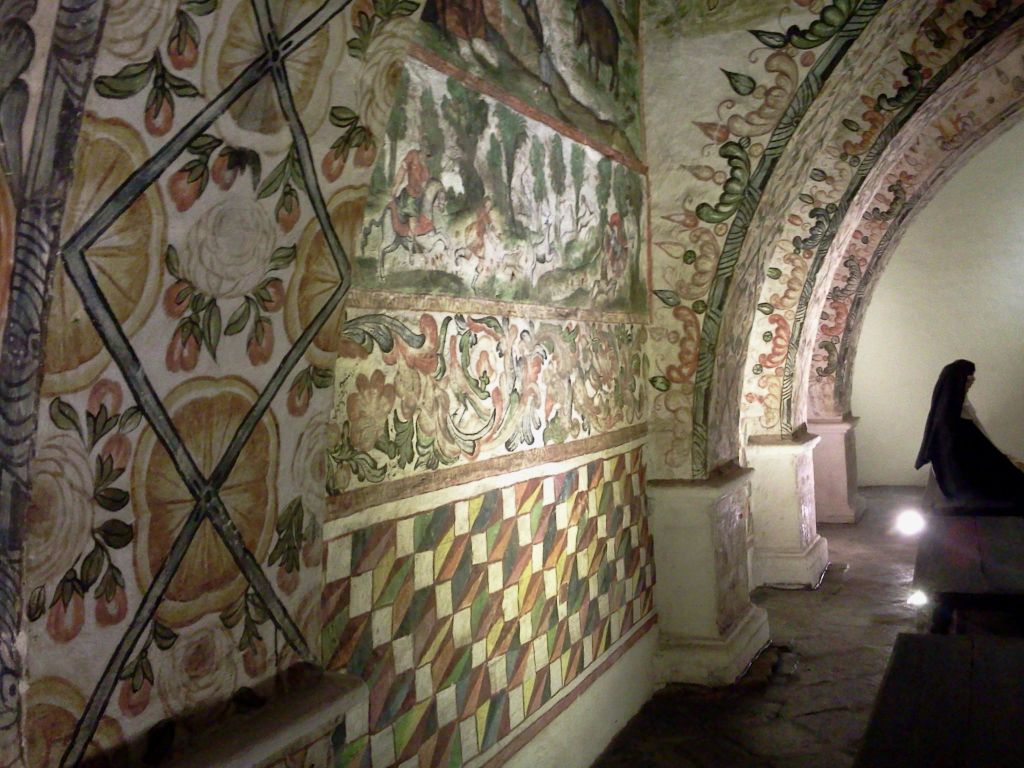 꽃과 기하학적 디자인을 포함하여 정교하고 밝은 색상의 프레스코화와 패턴으로 장식된 벽이 있는 역사적인 건물의 내부.