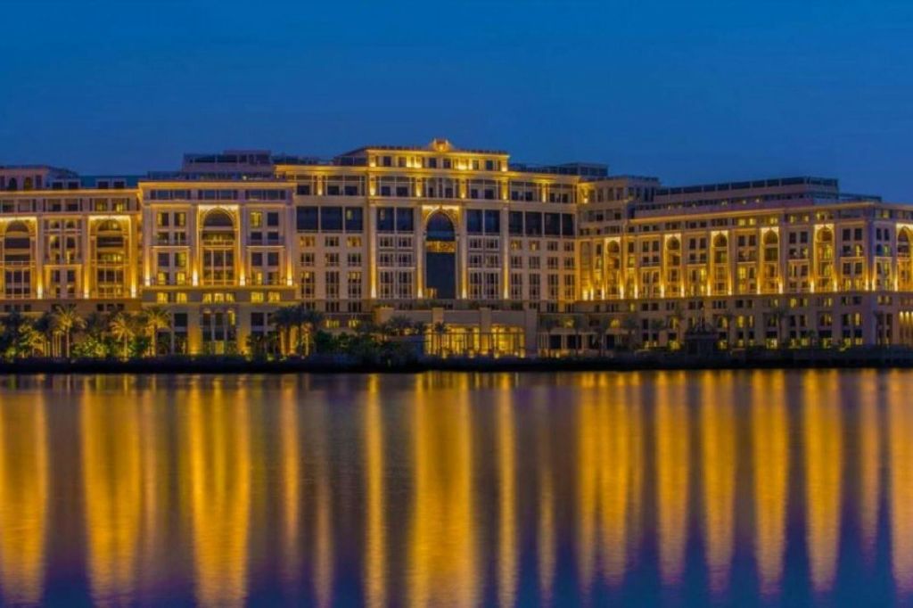 맑고 푸른 하늘 아래 잔잔한 물빛이 비치는 밤의 크고 환한 건물.