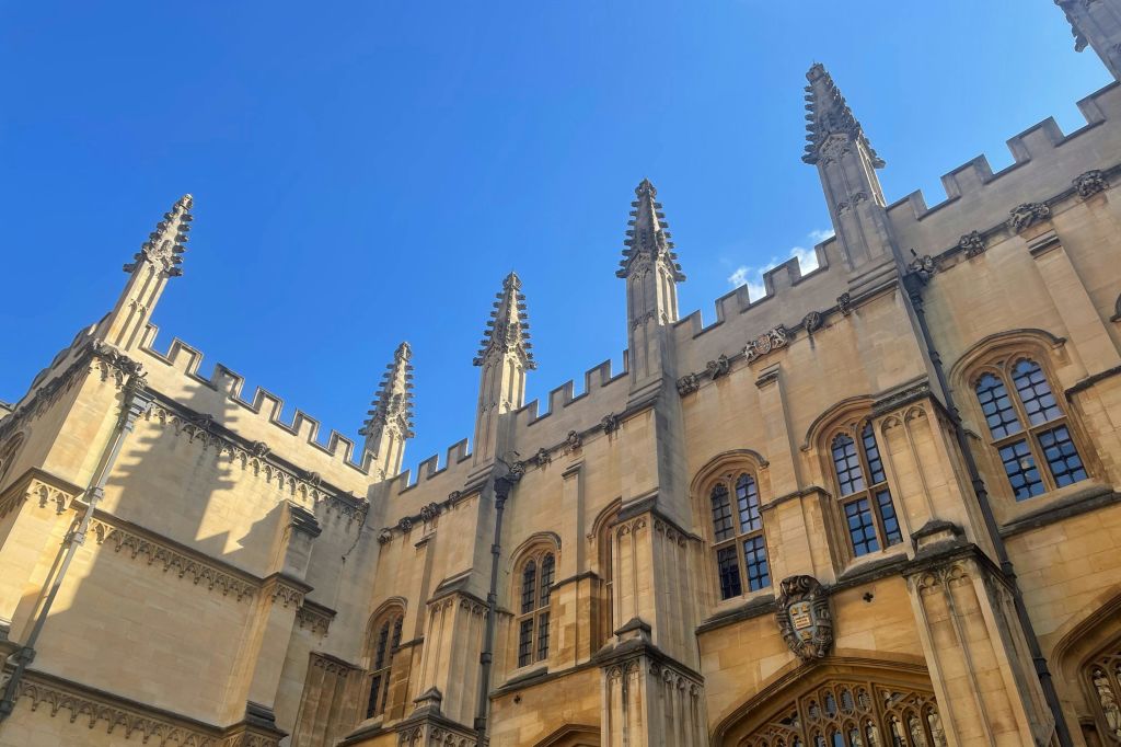 청명한 푸른 하늘을 배경으로 뾰족한 첨탑과 아치형 창문이 있는 유서 깊은 석조 건물.