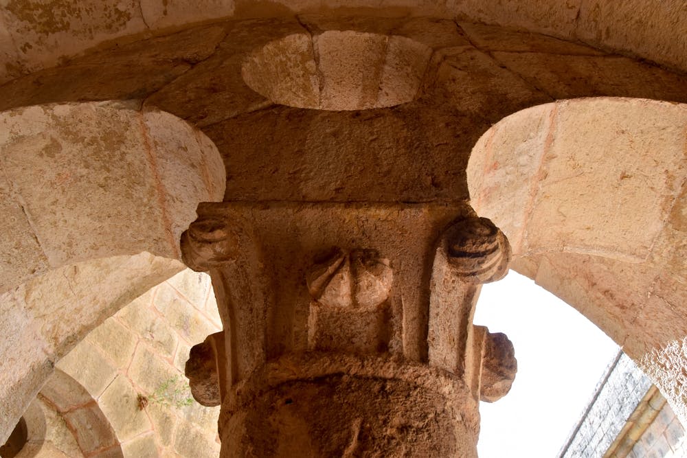 고대 석조 기둥의 클로즈업으로 아치를 받쳐주는 디테일한 조각으로 질감과 장인 정신을 강조합니다.