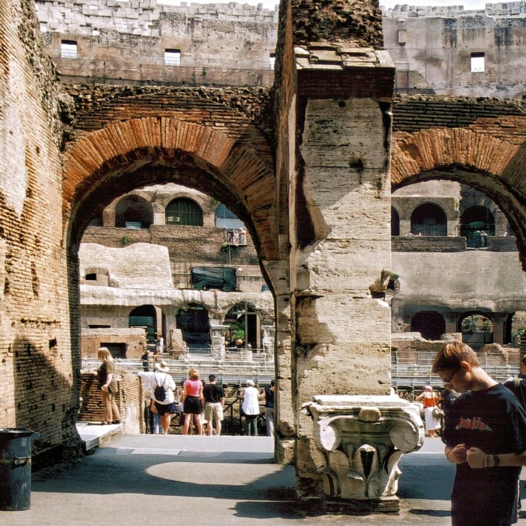 로마 콜로세움의 내부 유적지로 관광객들이 이곳을 탐험하고 배경에 석조 아치가 보입니다.